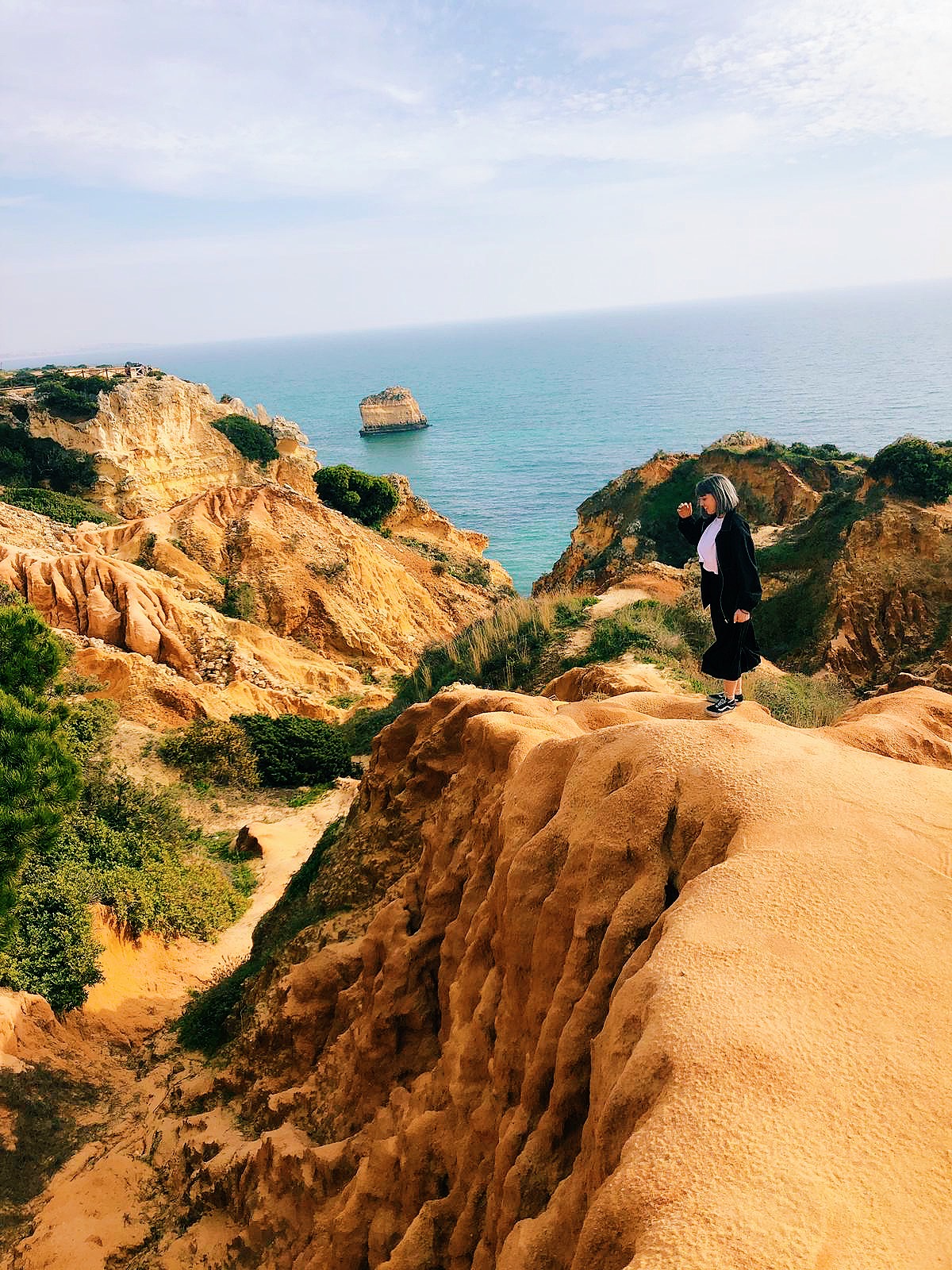 Alexa Klein standing on a cliff at Praia da Marinha in Lagoa, Portugal